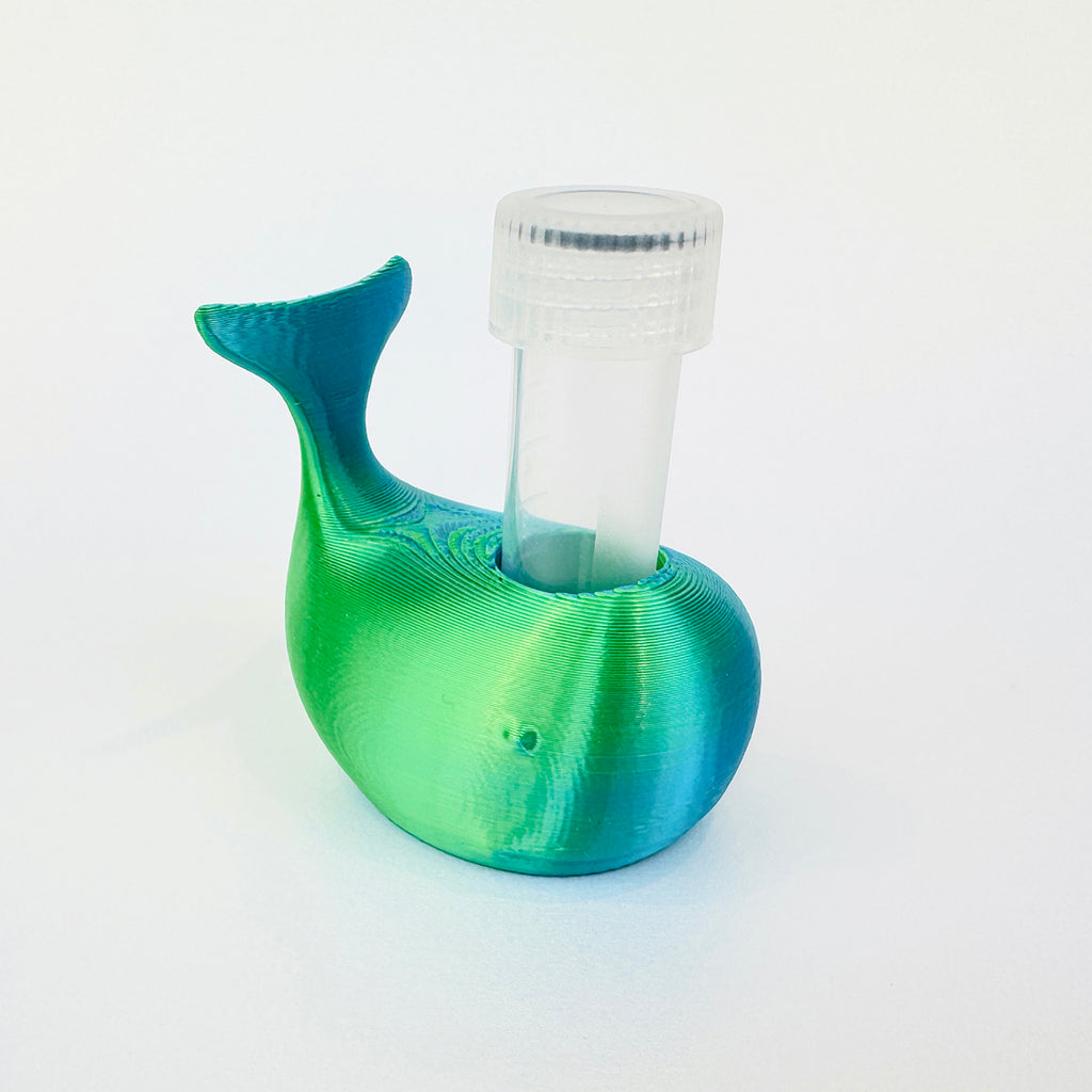 A 3D-printed whale-shaped holder with a clear plastic vial inserted into its back, shown on a clean white background.