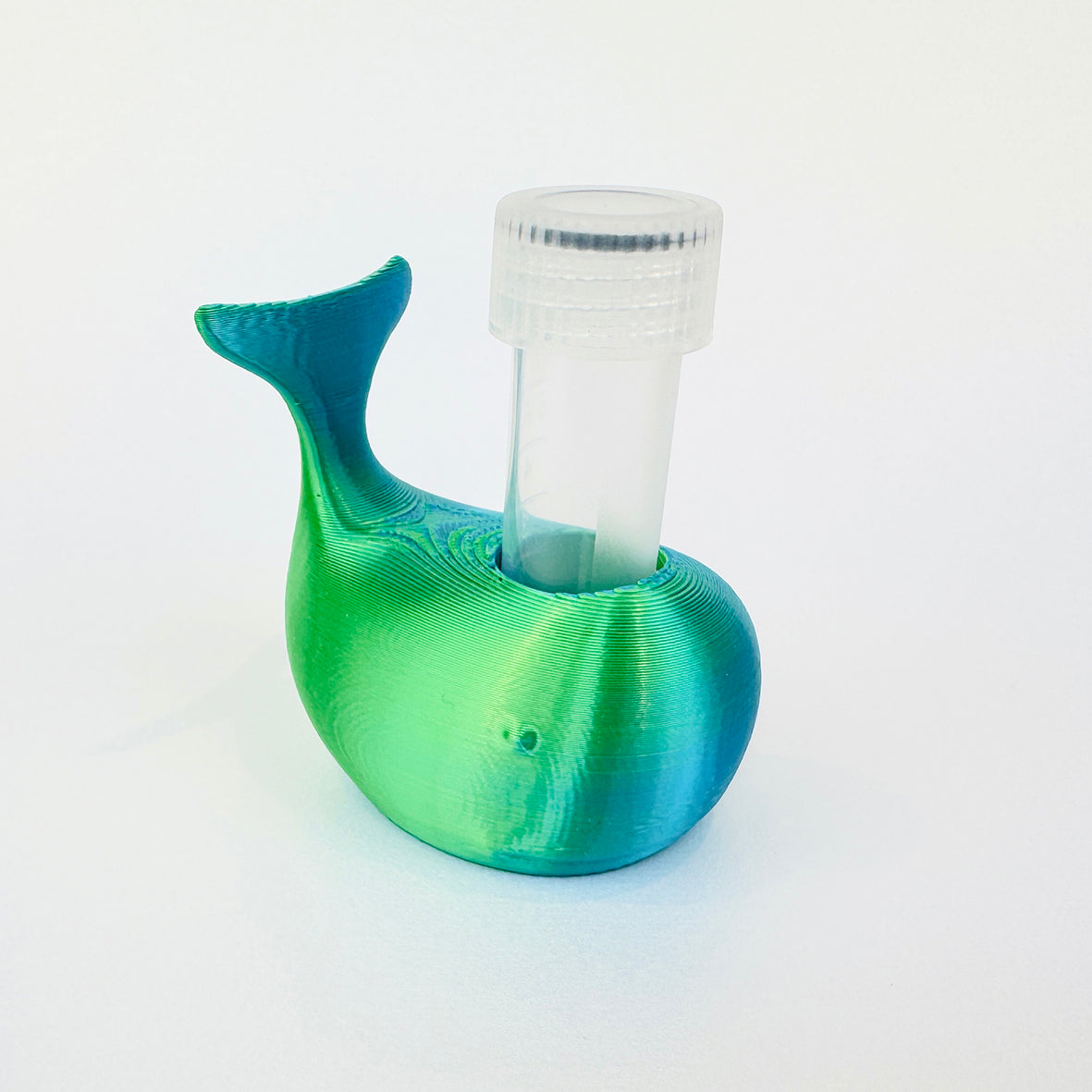 A 3D-printed whale-shaped holder with a clear plastic vial inserted into its back, shown on a clean white background.