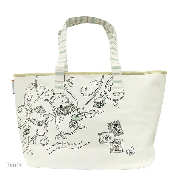 An off-white canvas tote bag featuring Alice in Wonderland themed illustrations, including the Cheshire Cat, teacups, and the quote 'After washing it for a minute or two, she made it out to be a gin'. The bag has striped handles in green and white and is shown against a plain white background.